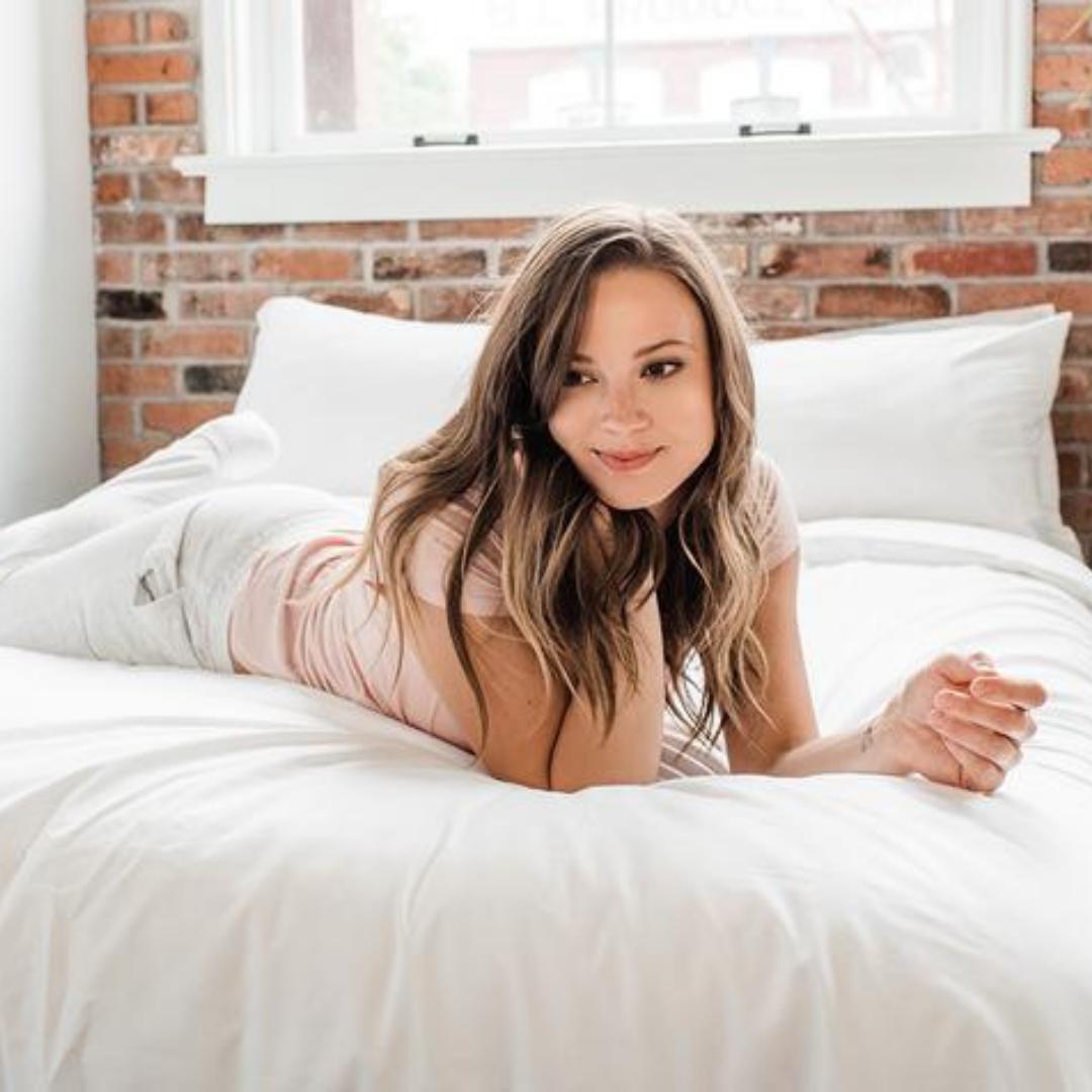 Woman in white laying across Haven Mattress with Starlight White bedding