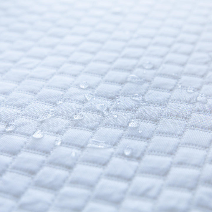 close up of water droplets on top of a Bedface Artic Cooling Mattress protector showcasing that it is waterproof