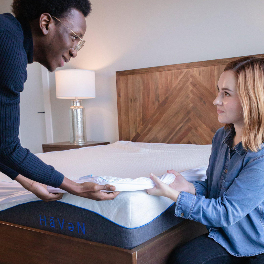 man and woman covering the edge of a Bedface Silver Mattress protector over the corner of Haven Mattress