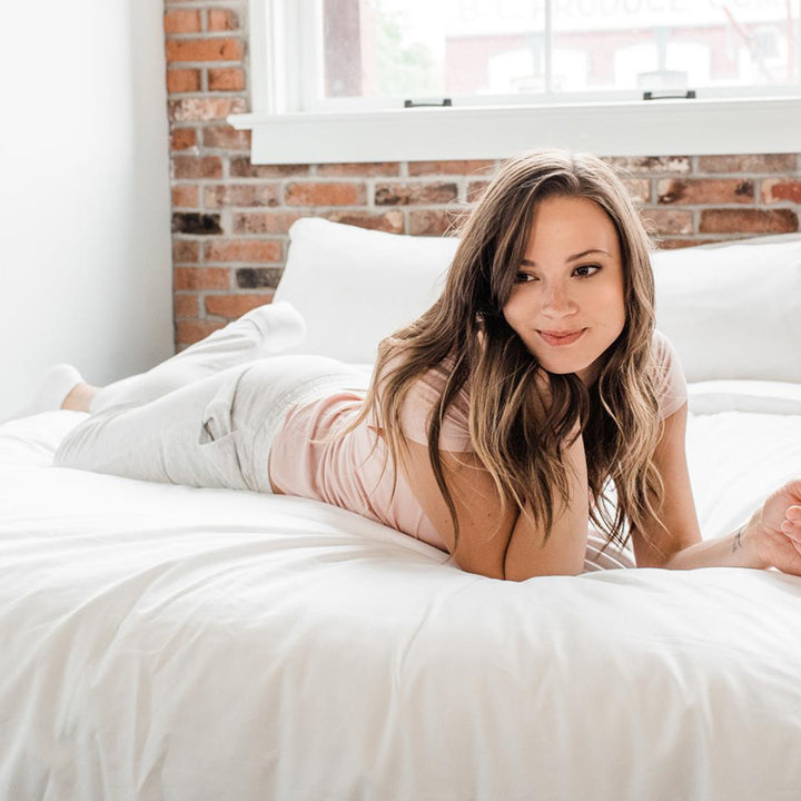 Woman in white laying across Haven Mattress with Starlight White bedding 
