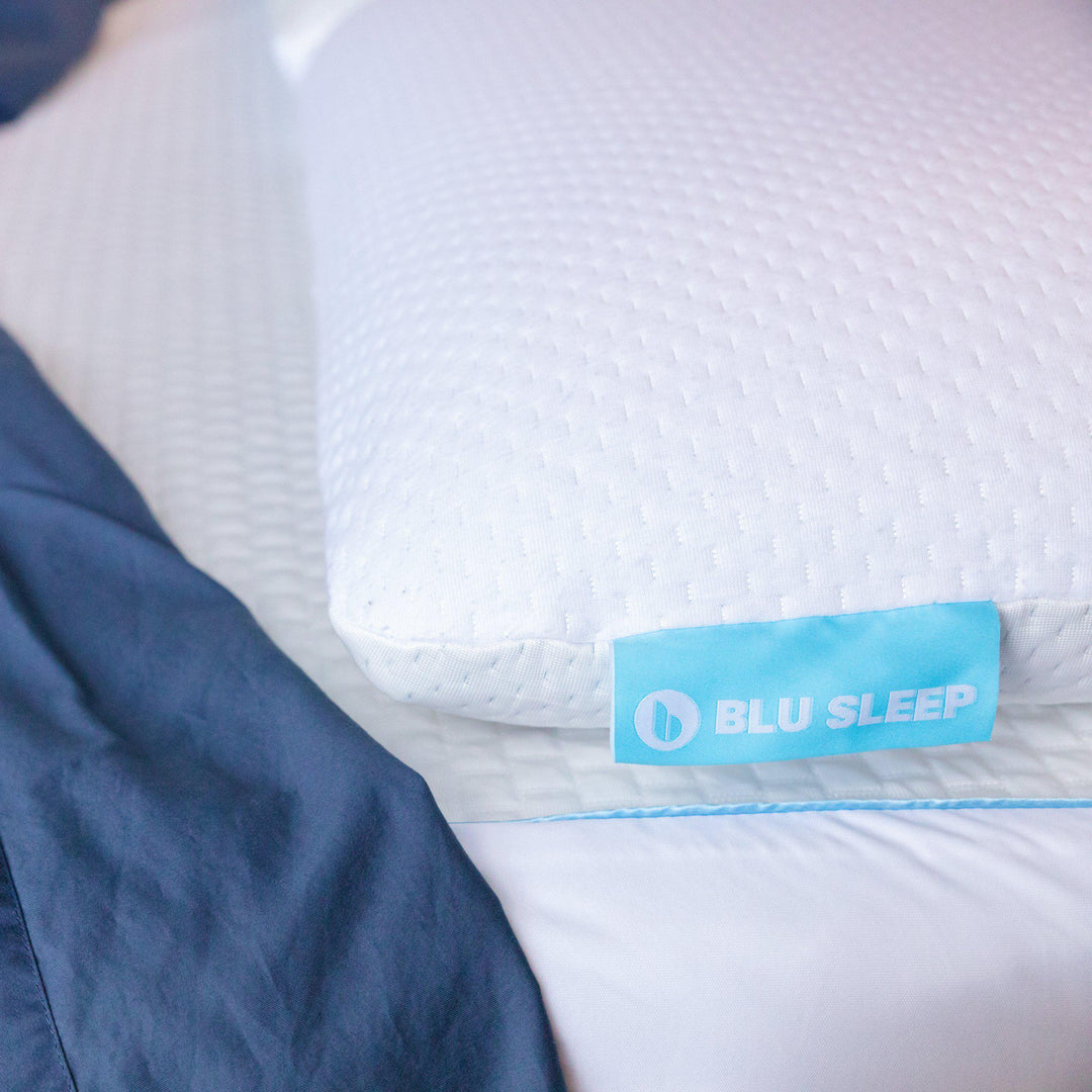 Close up of Bedface Blue Sleep Artic Cooling pillow protector covering a memory foam pillow on top of a Artic cooling mattress protector with a navy blue sheet folded down